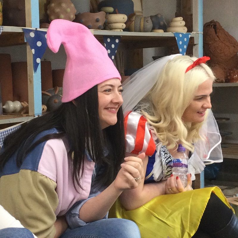 hen party dressed as snow white and her seven dwarfs enjoying watching their friends make pots on the potter's wheel at eastnor pottery