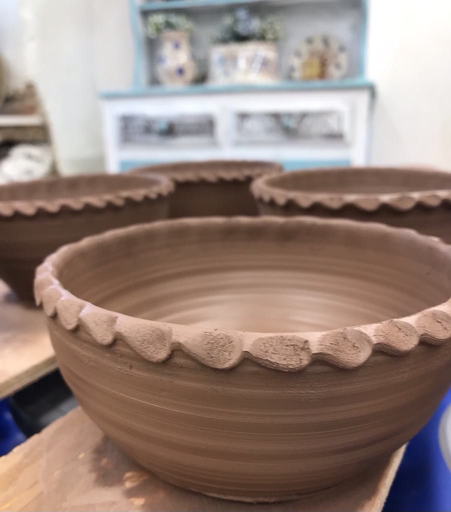 Freshly thrown terracotta  bowls with a pie crust rim made by Sarah Monk Ceramics in the studio at Eastnor Pottery. 