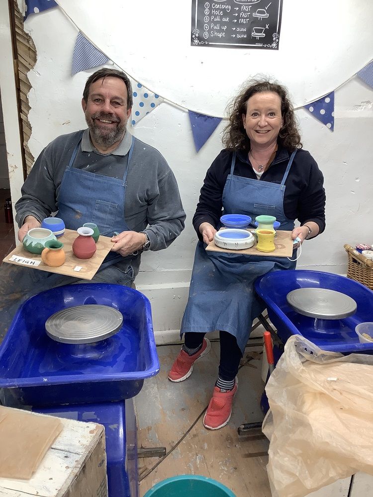 happy potters displaying their coloured pots made on a pottery weekend at eastnor pottery