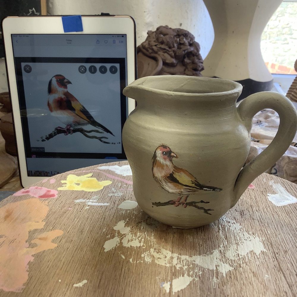 hand painted goldfinch on a potter's wheel thrown pot on a pottery course