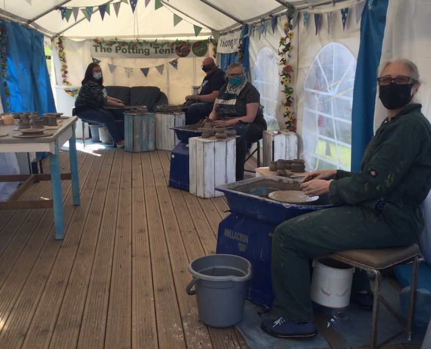 potters wheel course participants inside the potting tent at eastnor pottery