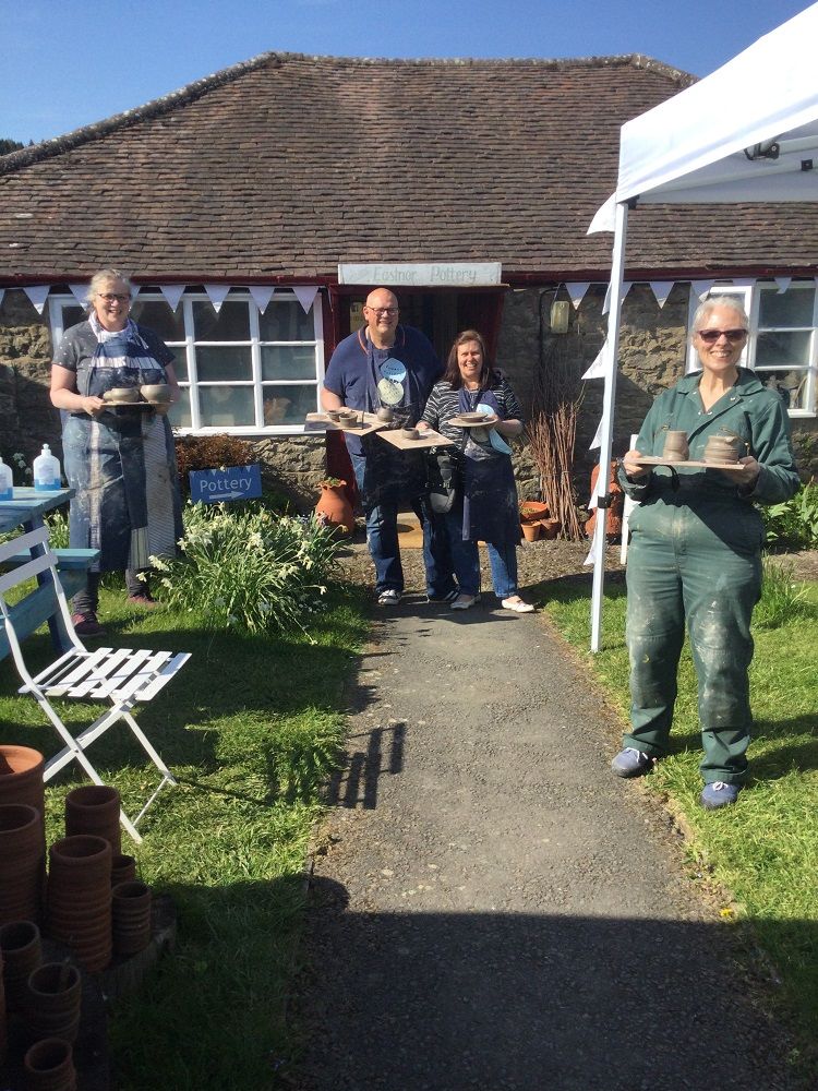 pottery wheel students outside eastnor pottery in herefordshire showing off their excellent pots