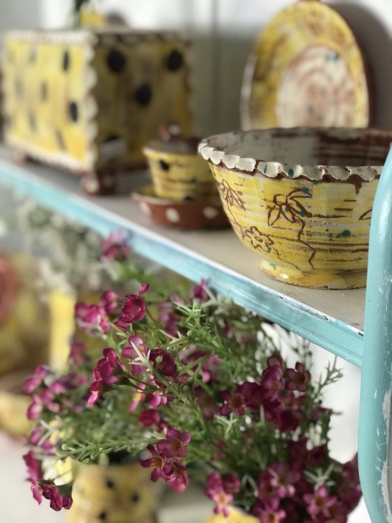 Yellow sgraffito  pottery by Sarah monk Ceramics displayed on a shelf at Eastnor Pottery