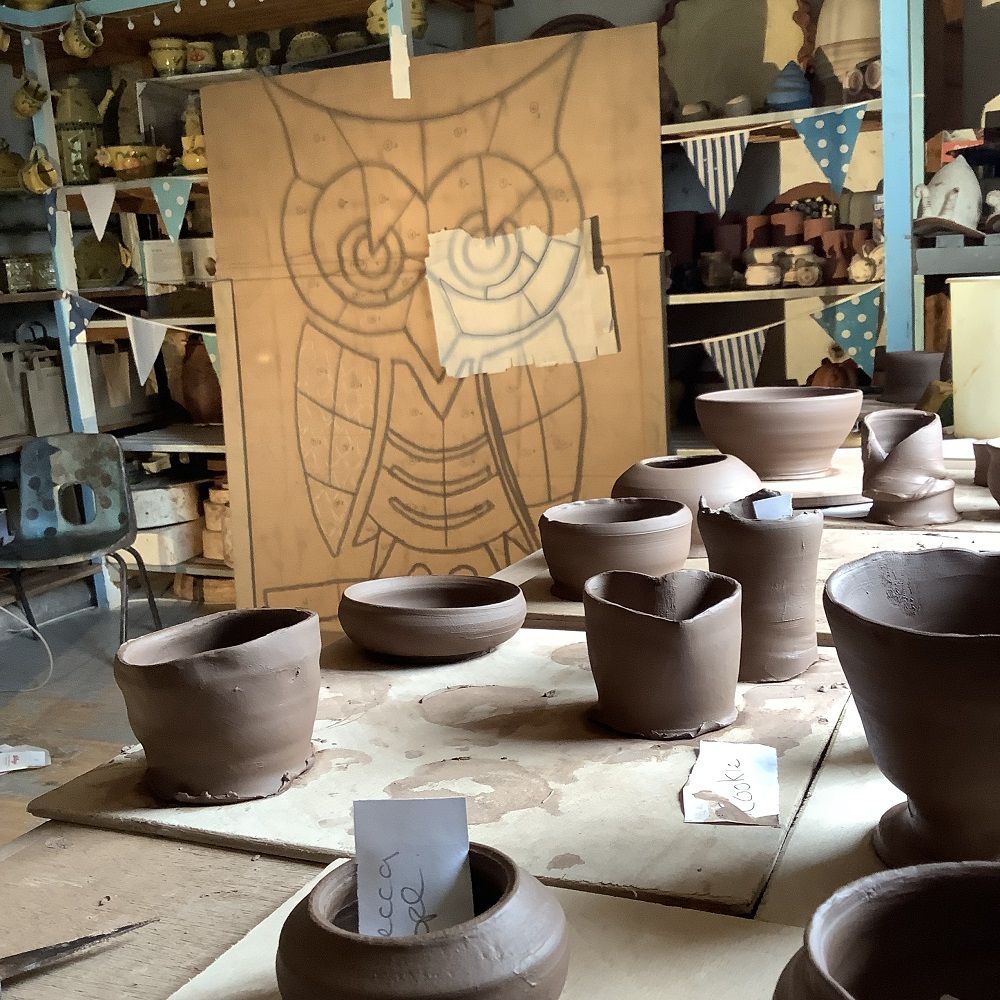 owl drawing in degments projected on to wooden board, with clay pots in the foreground