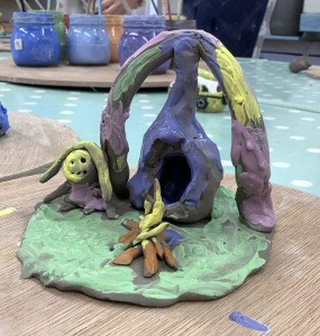 hand clay model depicting a glamping scene created by a child and painted with under glaze