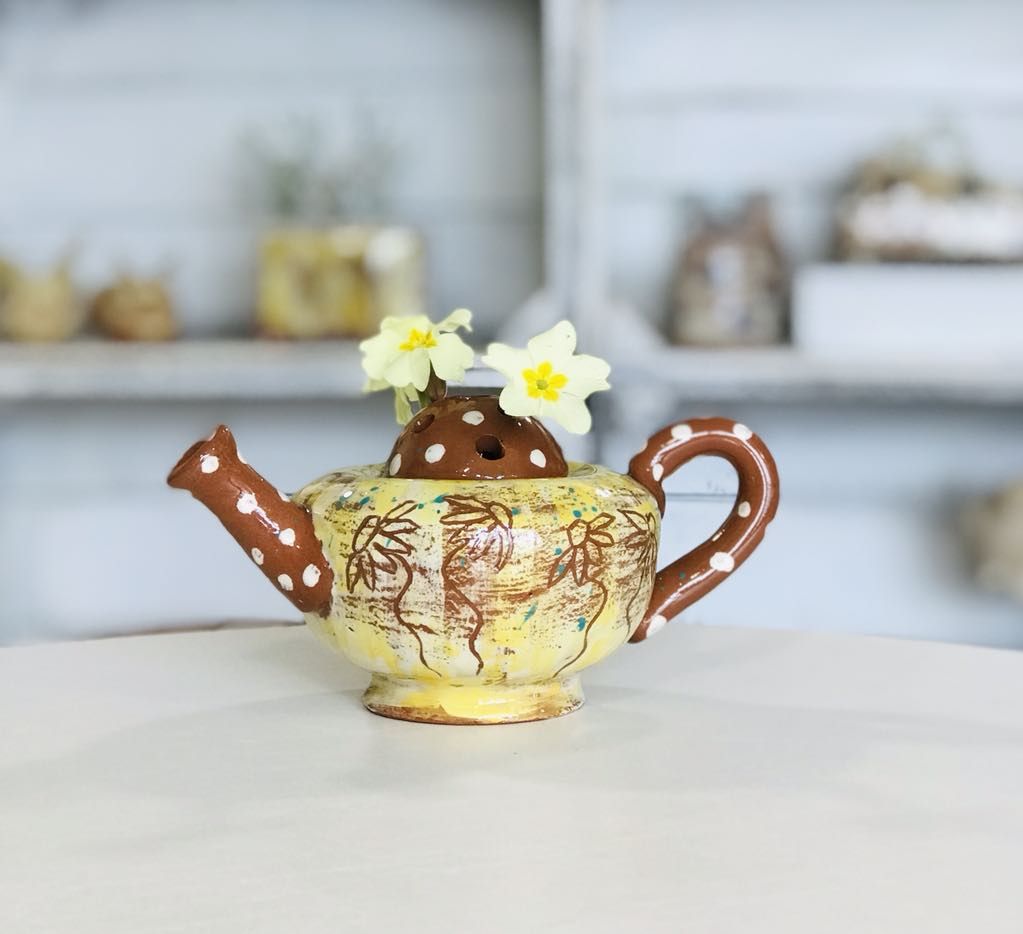 Yellow teapot /flower frog displayed with with fresh yellow primroses made by Sarah Monk Ceramics