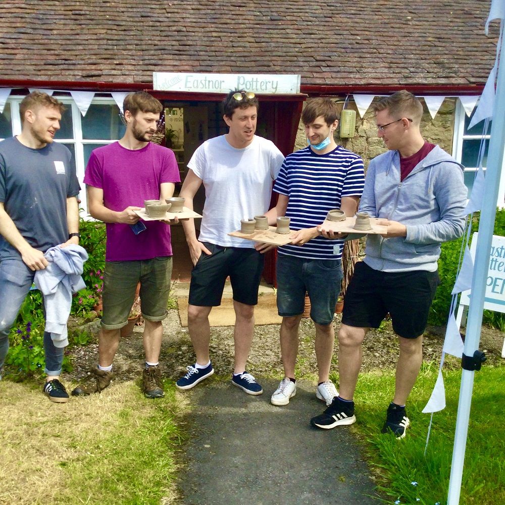 5 men stood outside eastnor pottery hold pots made on introductory session