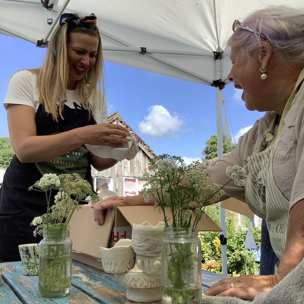 two women pulling pots out of a cardboard box smiling 