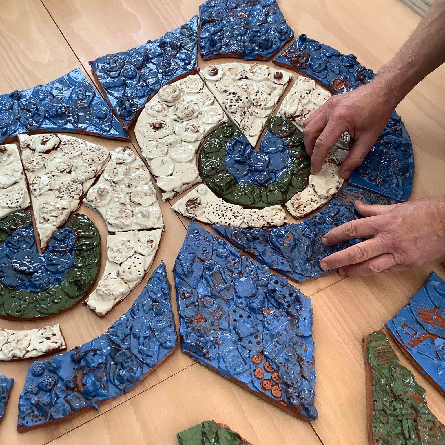 hand made pottery tiles made by children at grangefield primary school arranged in the shape of an owl - the school logo