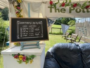 black chalk bard style poster reading 'eastnor's step by step' inside a white marque, on a white table next to a blue sofa which greenery outside