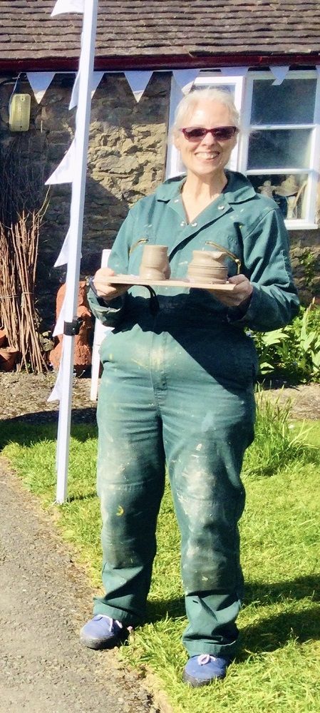 pottery participant wearing a green boiler suit to potters wheel weekend course