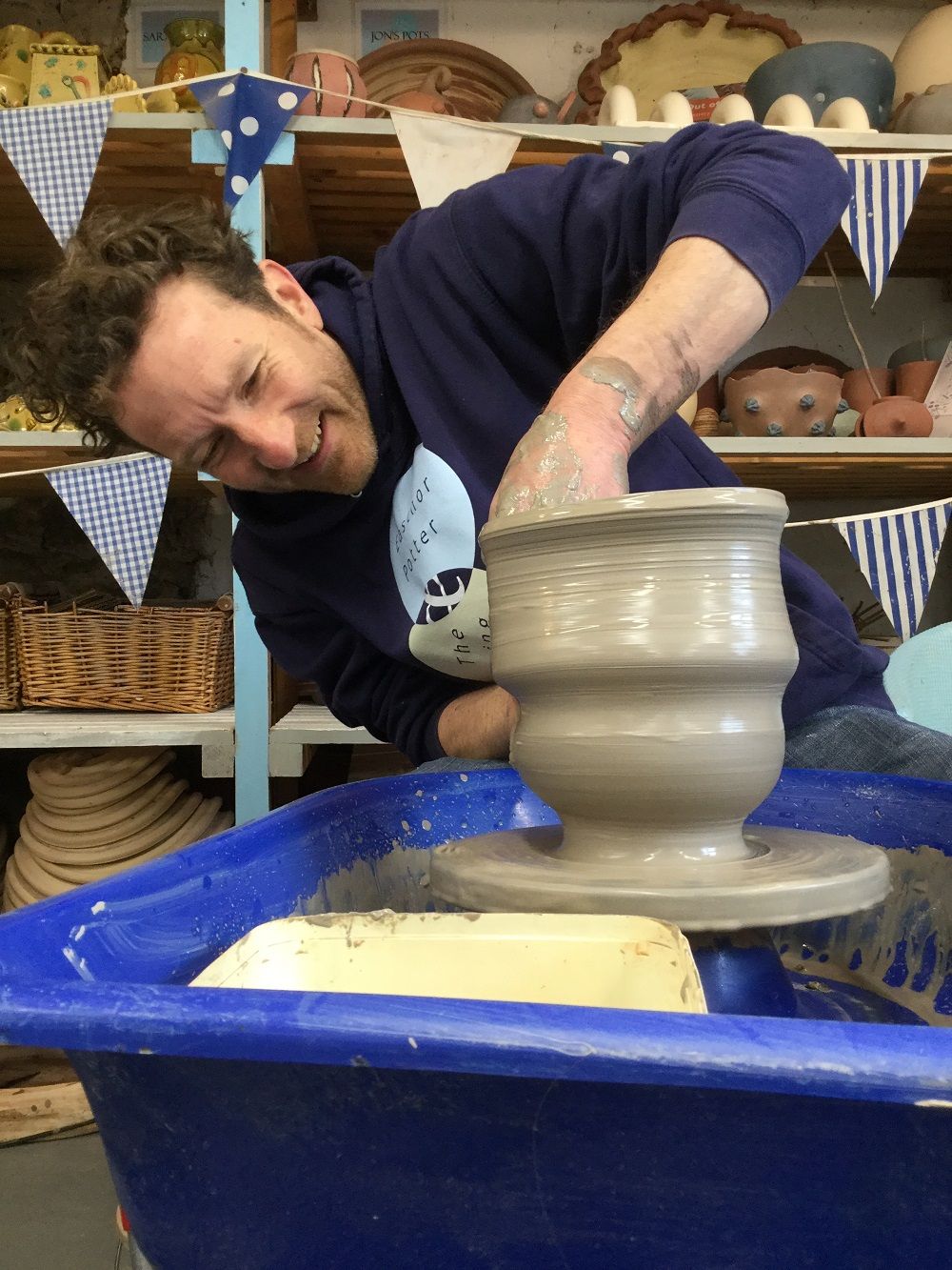 jon williams from eastnor pottery smiling and making a pot on the potter's wheel