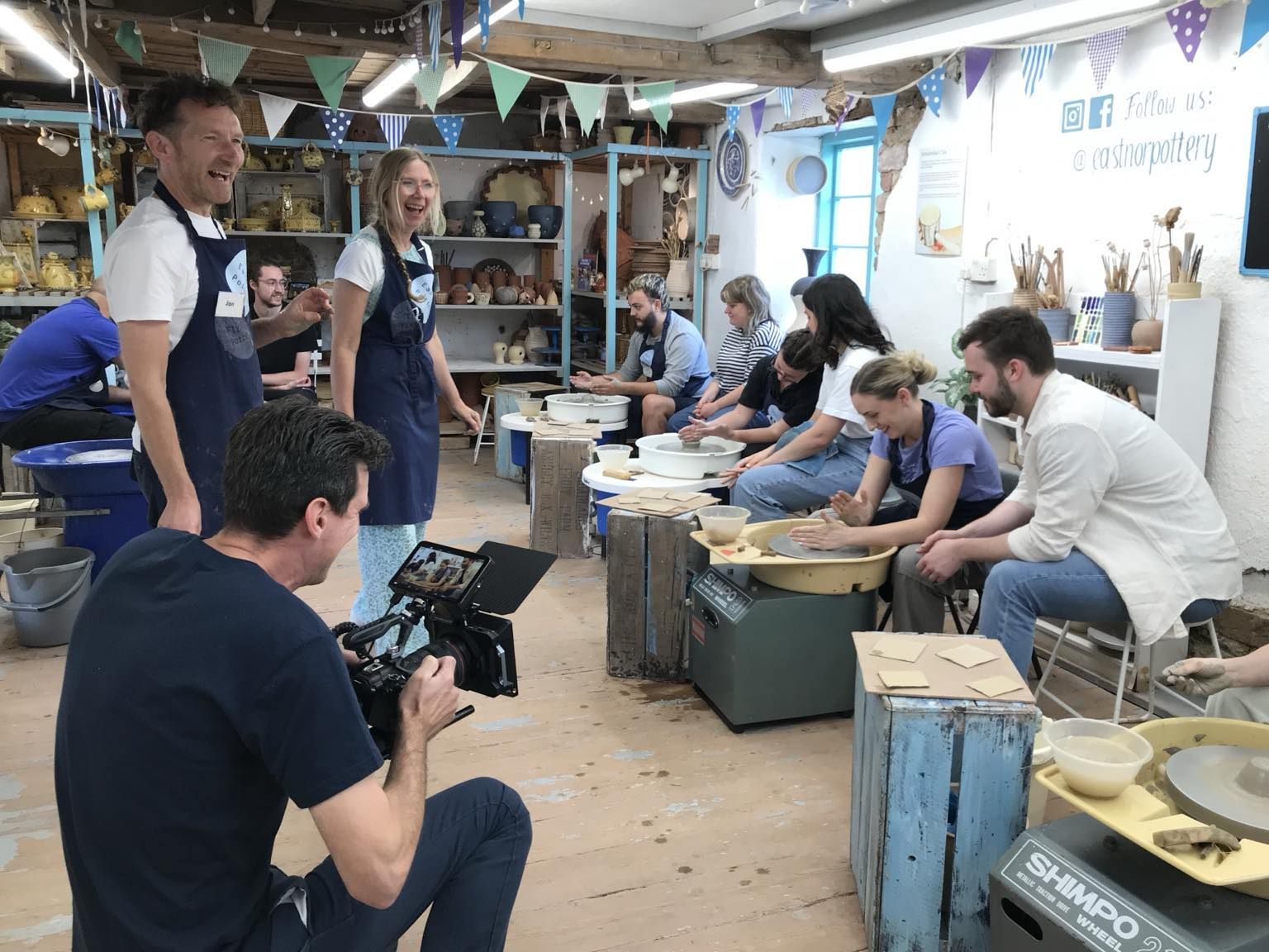 photopiauk cameraman filming six smiling and laughing people on the potter's wheels