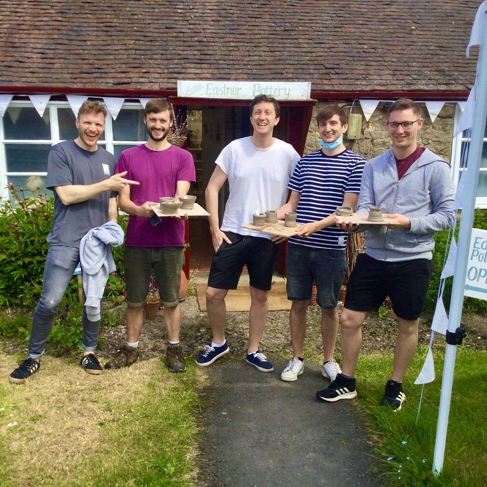 5 men stood outside eastnor pottery hold pots made on introductory session