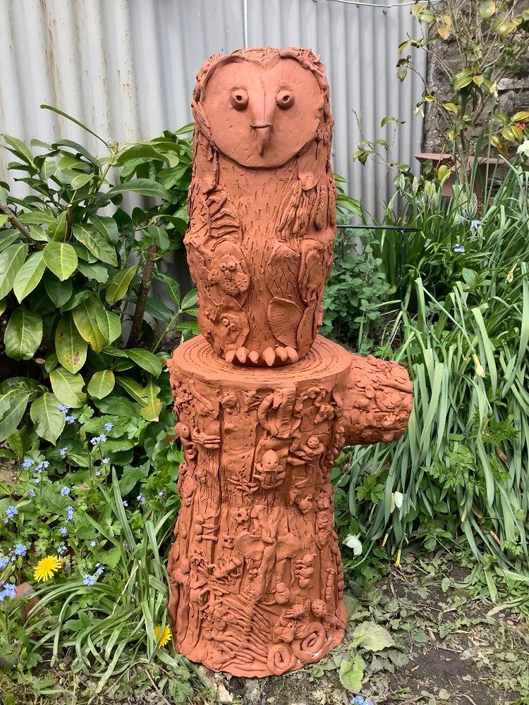 collaborative terracotta barn owl sat on a terracotta tree stump encrusted with bugs made by school children