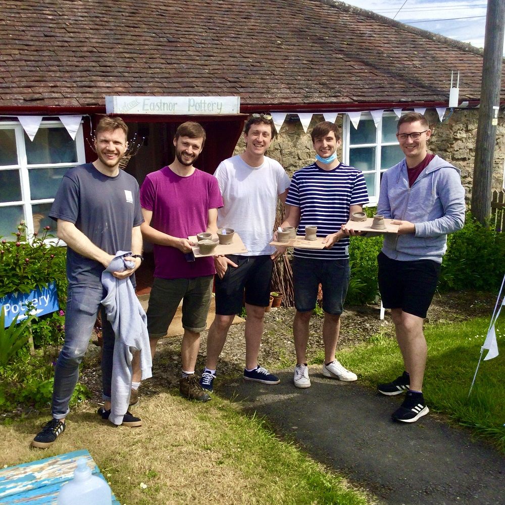 5 men stood outside eastnor pottery hold pots made on introductory session