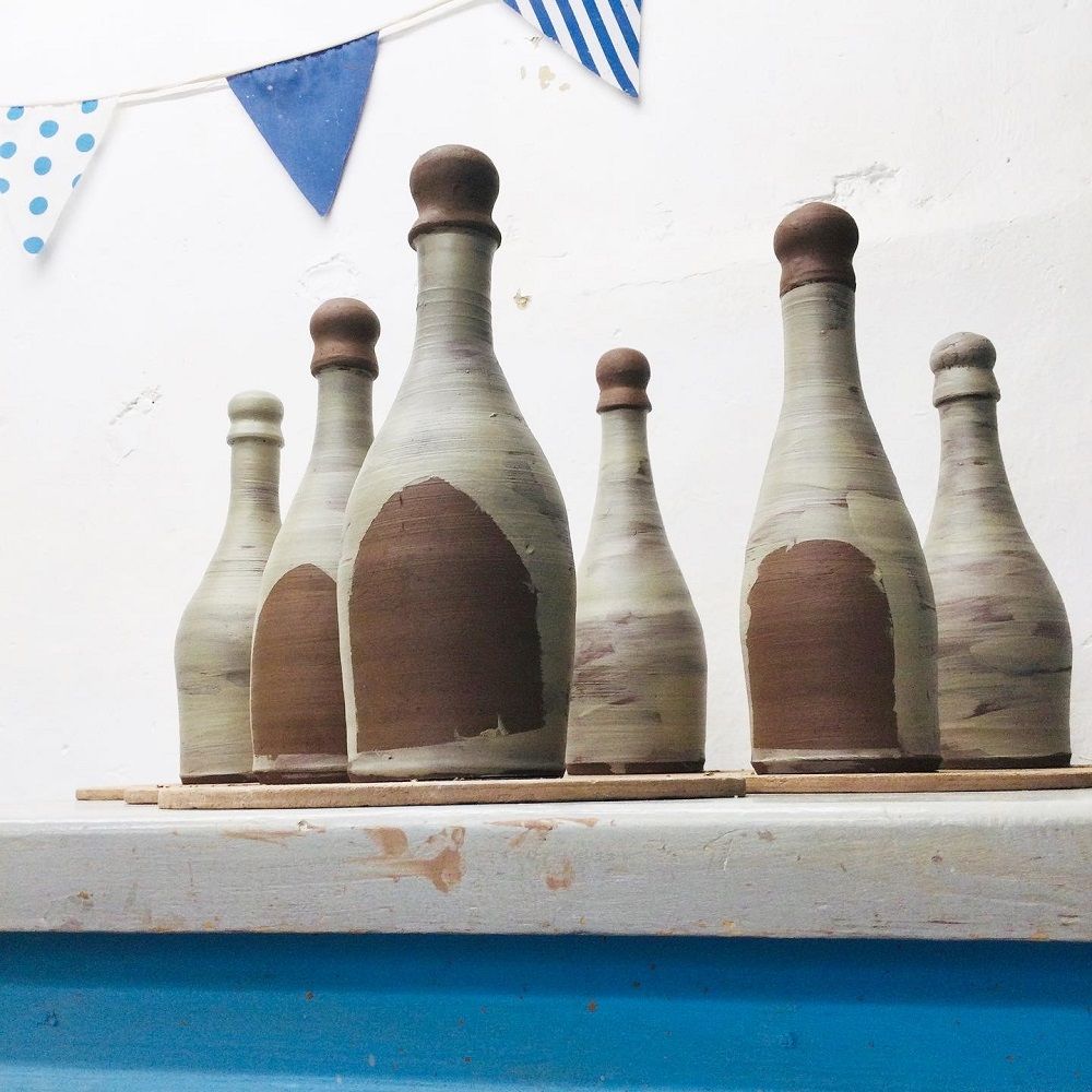 hand thrown terracotta bottles painted with white slip on table