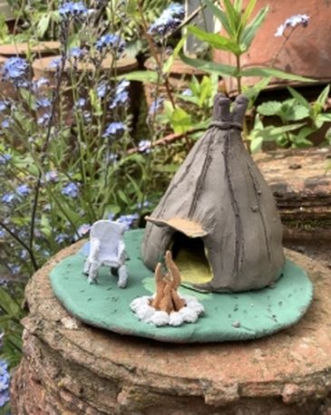 clay hand modeled tepee with green base, fire and white chair