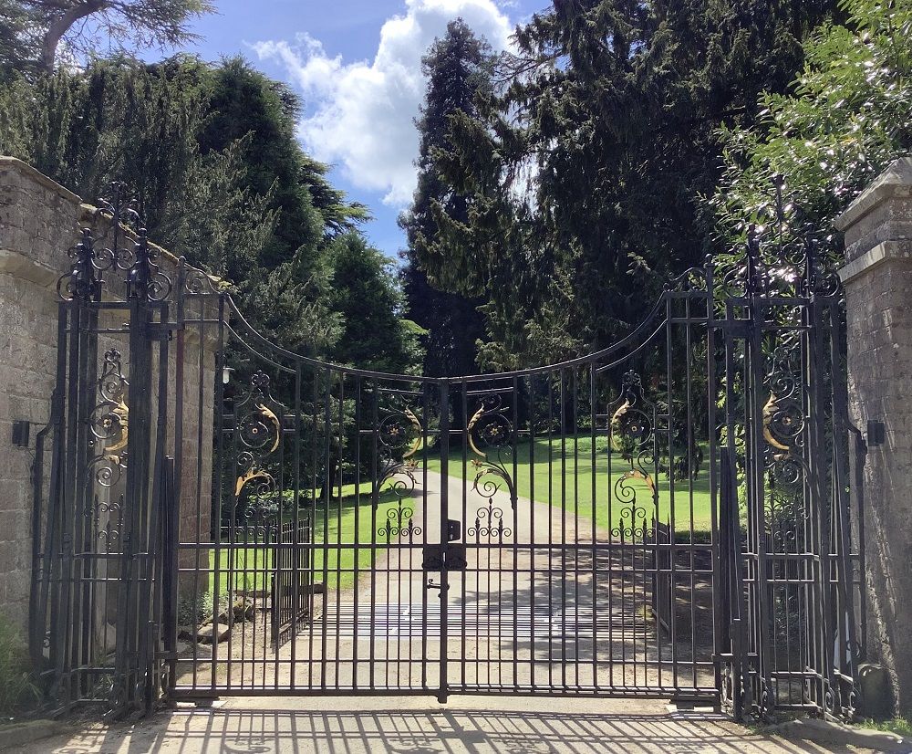 black and gold gates leading to eastnor castle with driveway path behind