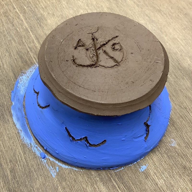 pottery course participants scratch a monogram into the base of a pot