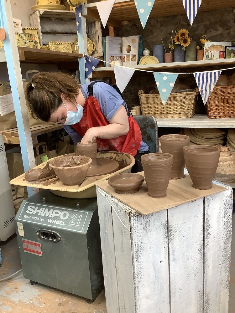 lady throwing pot on weekend pottery course surrounded by pots she had thrown previously