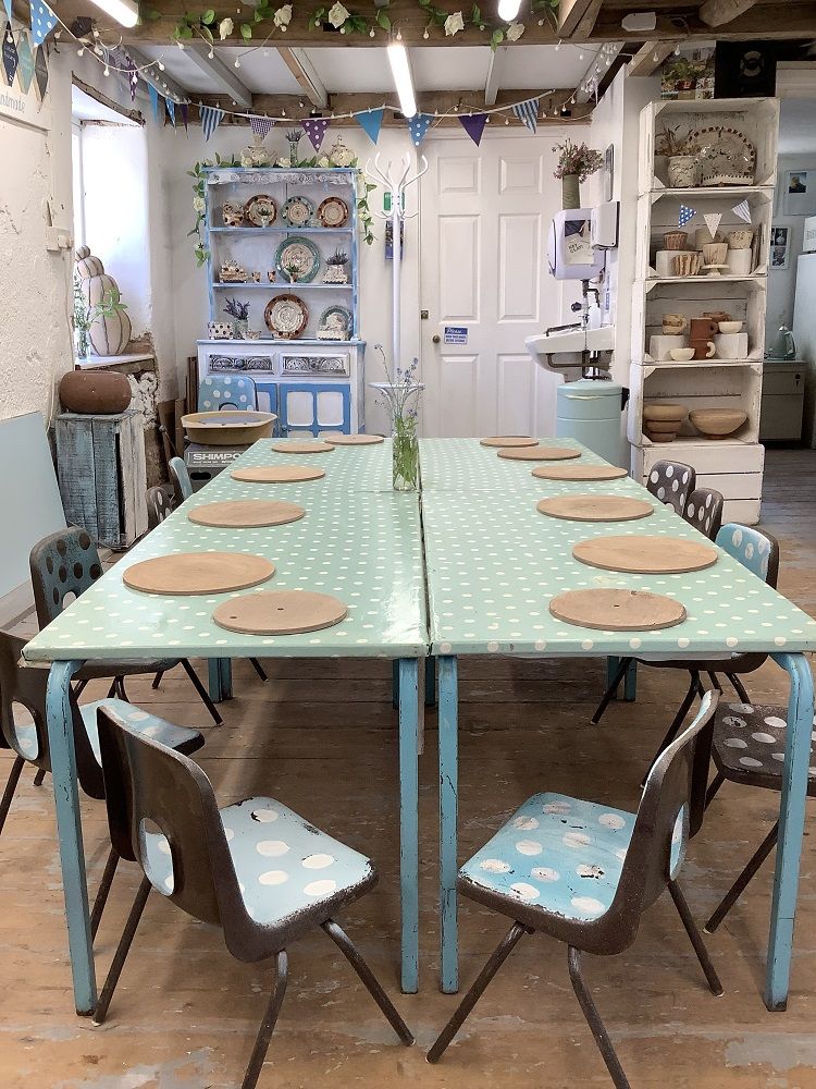 table with round wooden boards and children's chairs surrounding ready for a clay modelling session