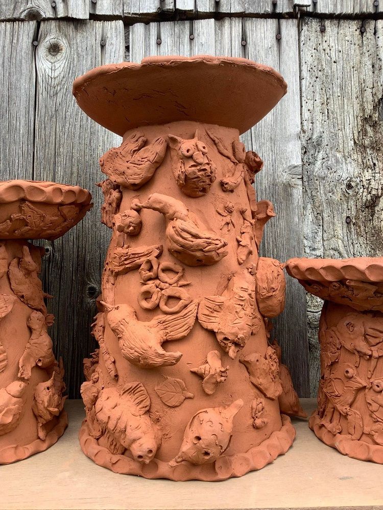 three terracotta bird baths covered in garden birds made by school children