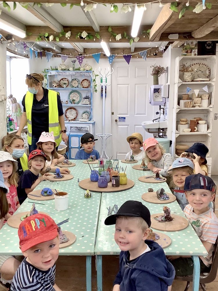 group of children sat around table taking part in a hand clay modelling session